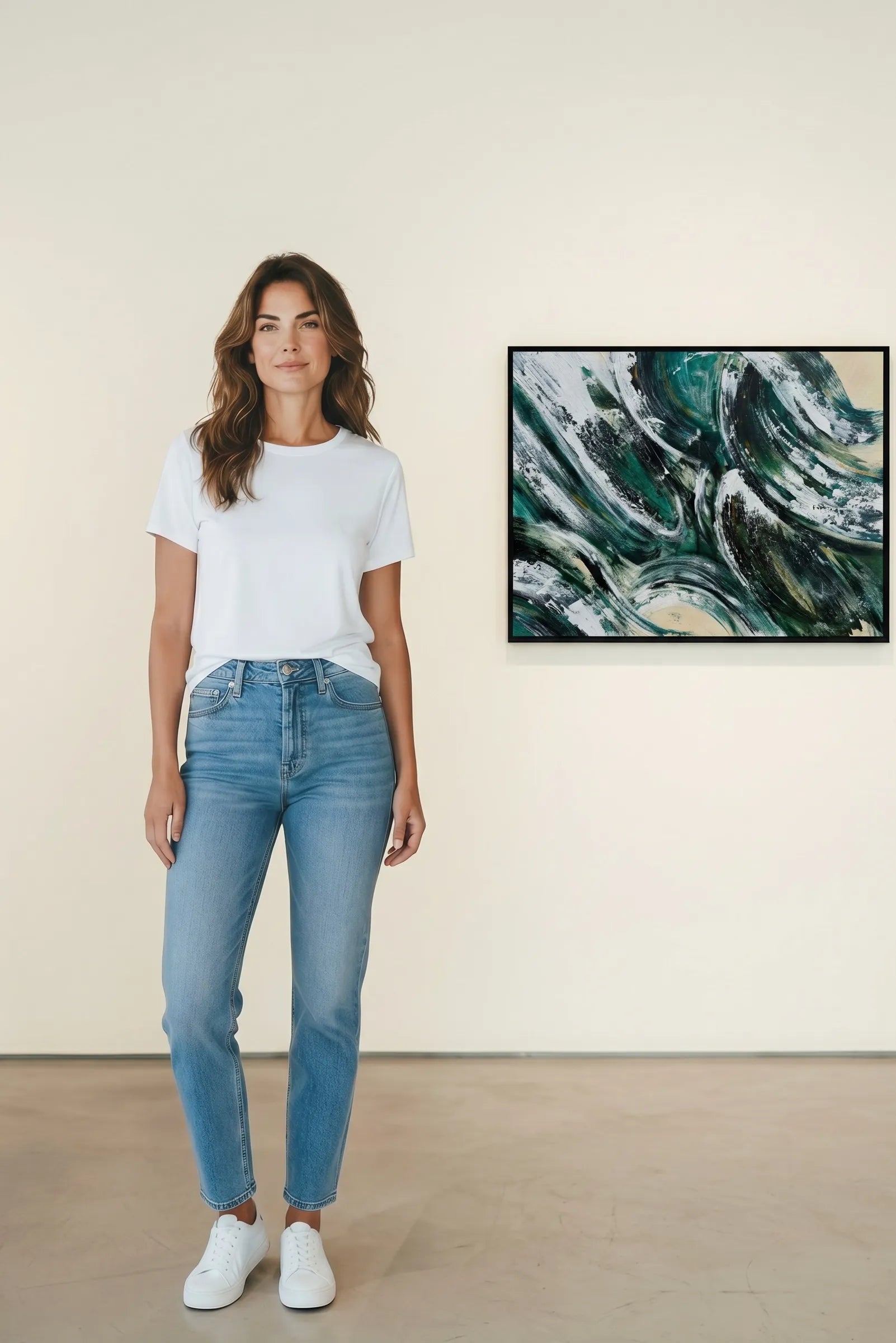 Woman wearing a white t-shirt and blue jeans standing in front of abstract wall art by Charlotte Gibbs.