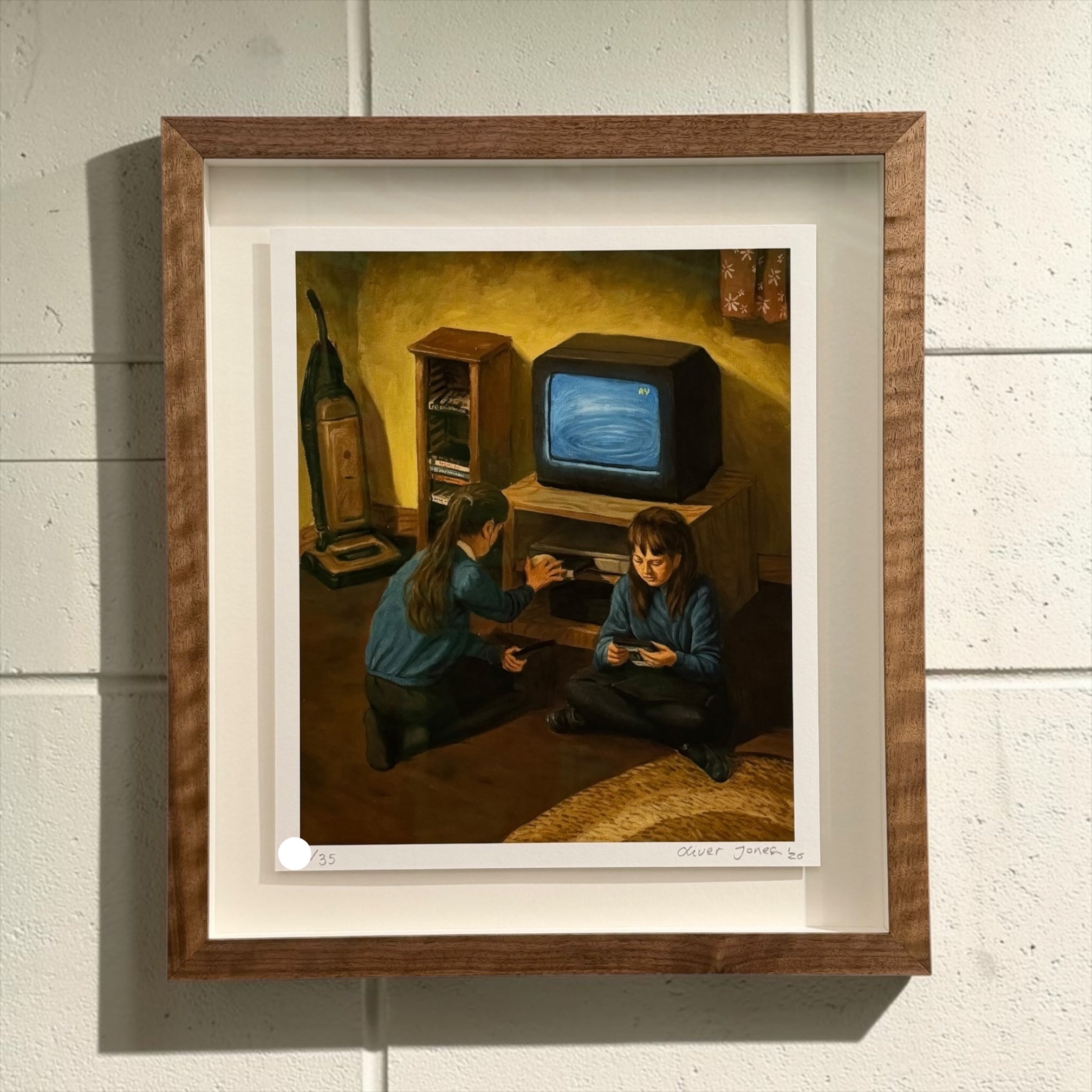 A framed art print featuring a painting of two children in a dimly lit room with a vintage television, mounted on a white paneled wall.