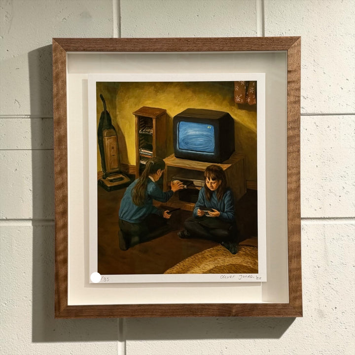 A framed art print featuring a painting of two children in a dimly lit room with a vintage television, mounted on a white paneled wall.