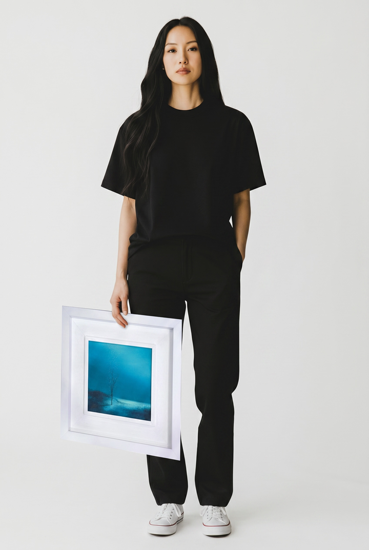 Person holding a framed artwork by Vincent Devine against a plain background