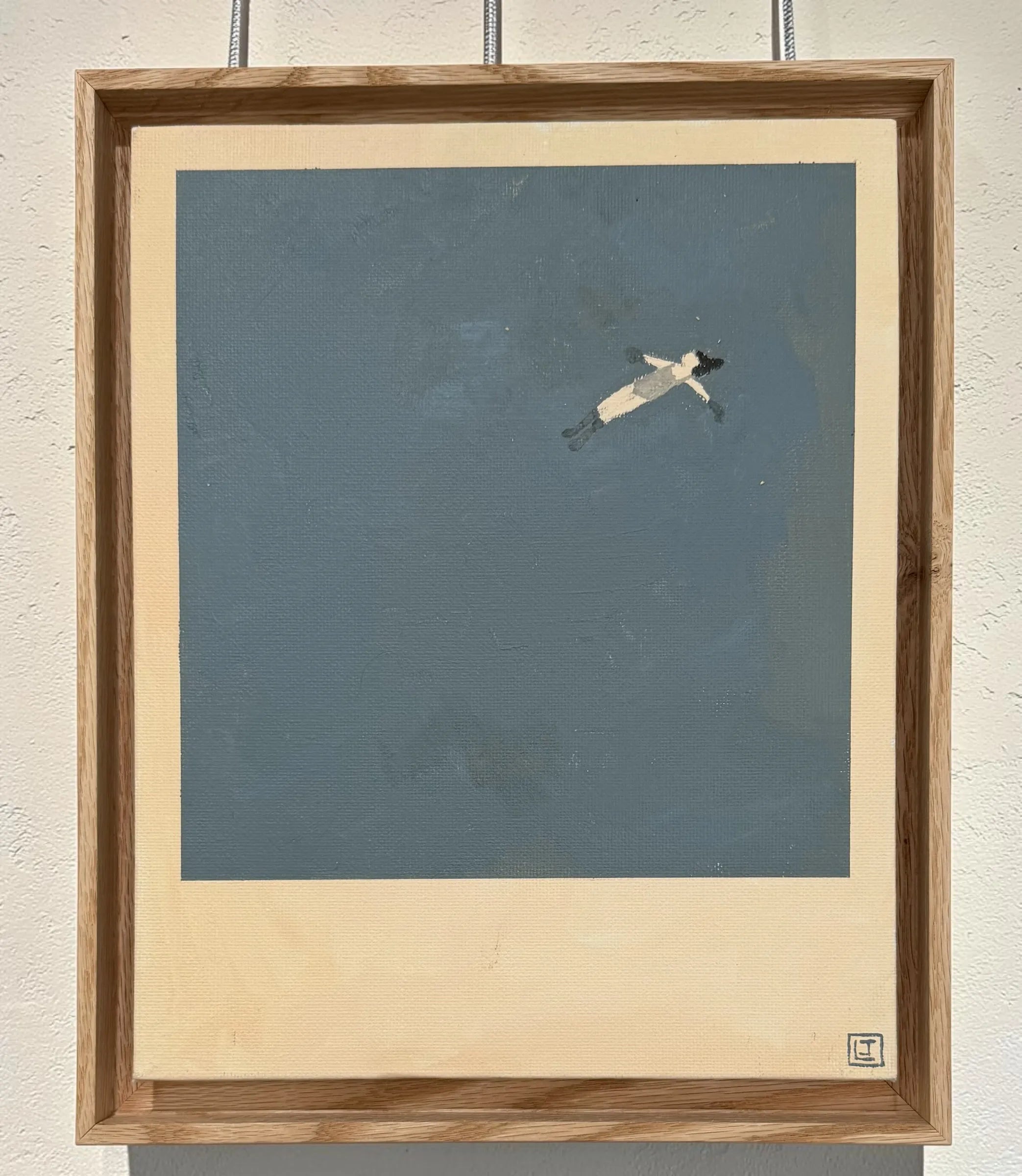 Framed artwork of a person floating on water against a blue background