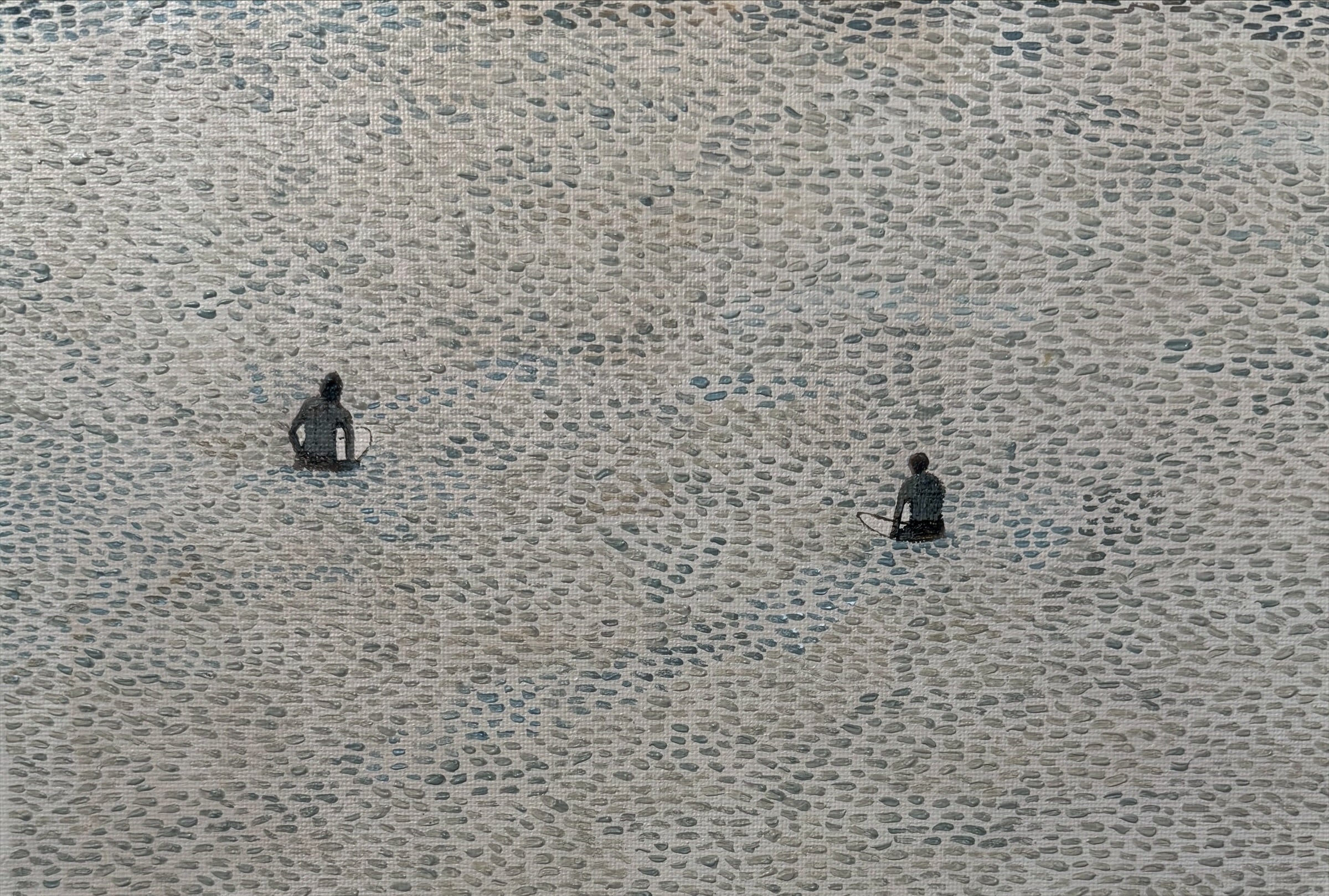 Two surfers sitting on a textured water surface waiting for a wave