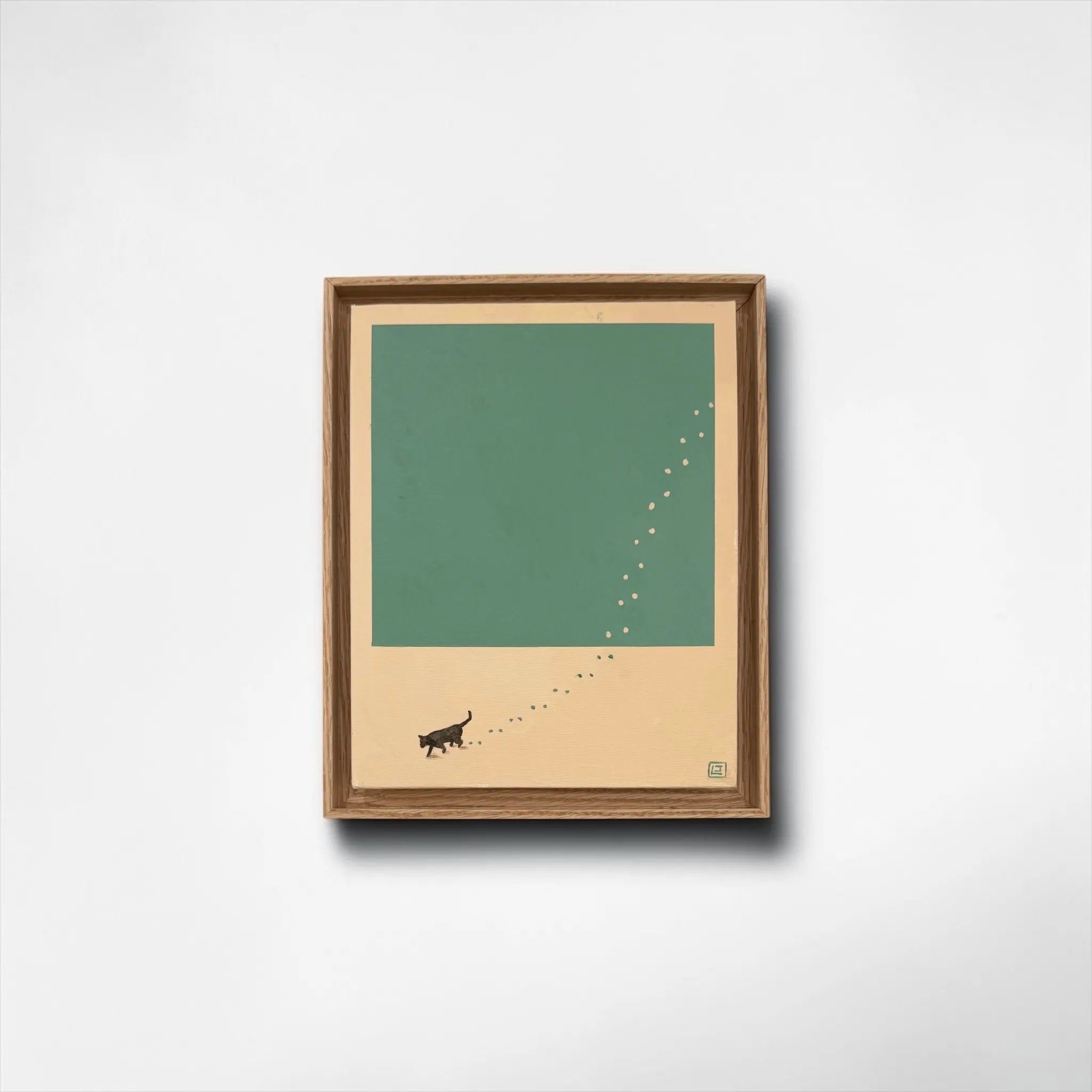 Framed artwork with a minimalist design of a cat and paw prints on a green paint and beige background.