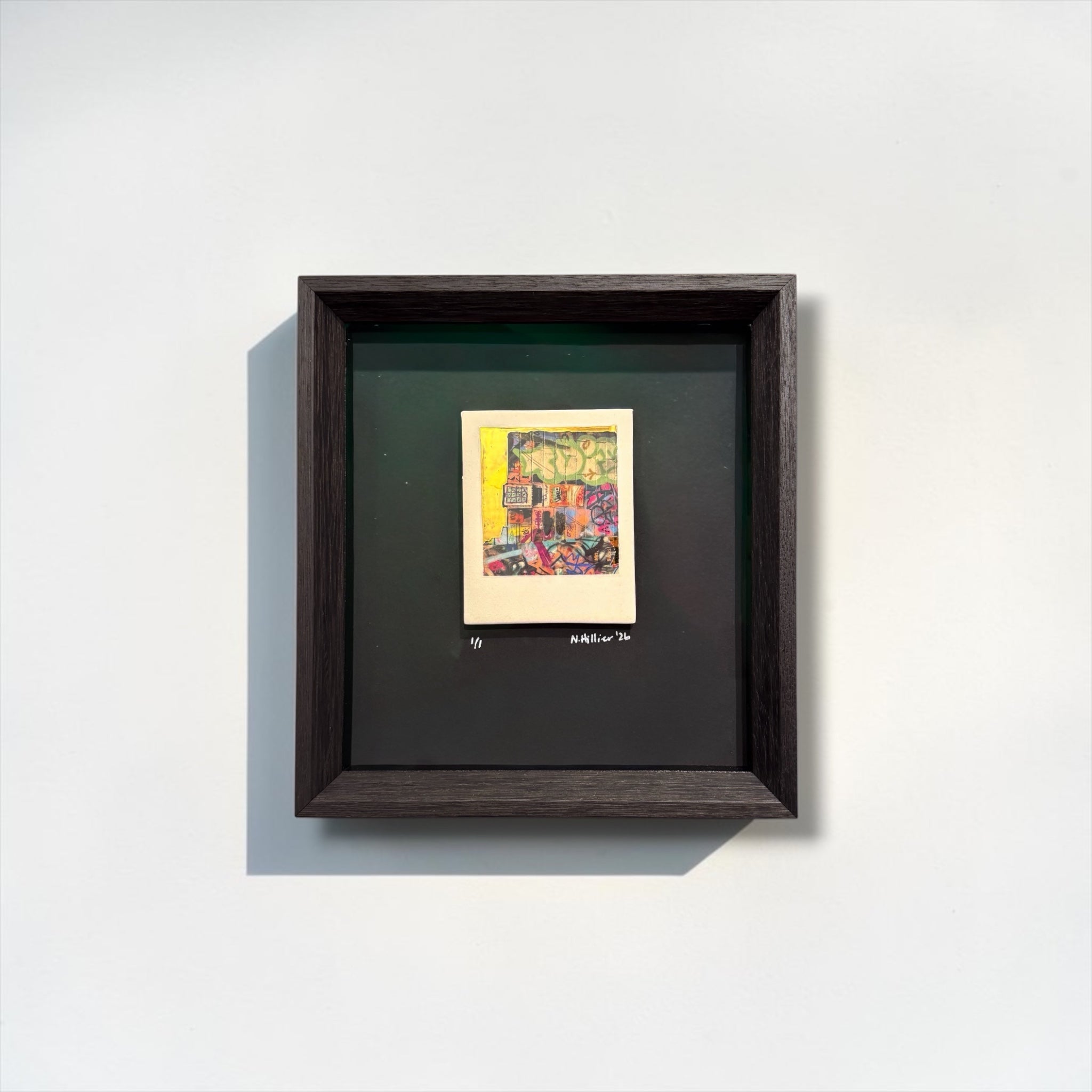 Framed artwork by Nadia Hillier with a colorful abstract design on a white wall