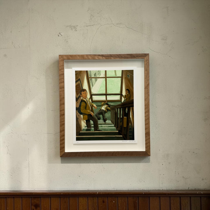 A framed art print depicting a scene of people on a staircase, mounted on a textured light gray wall above a dark wood panel.
