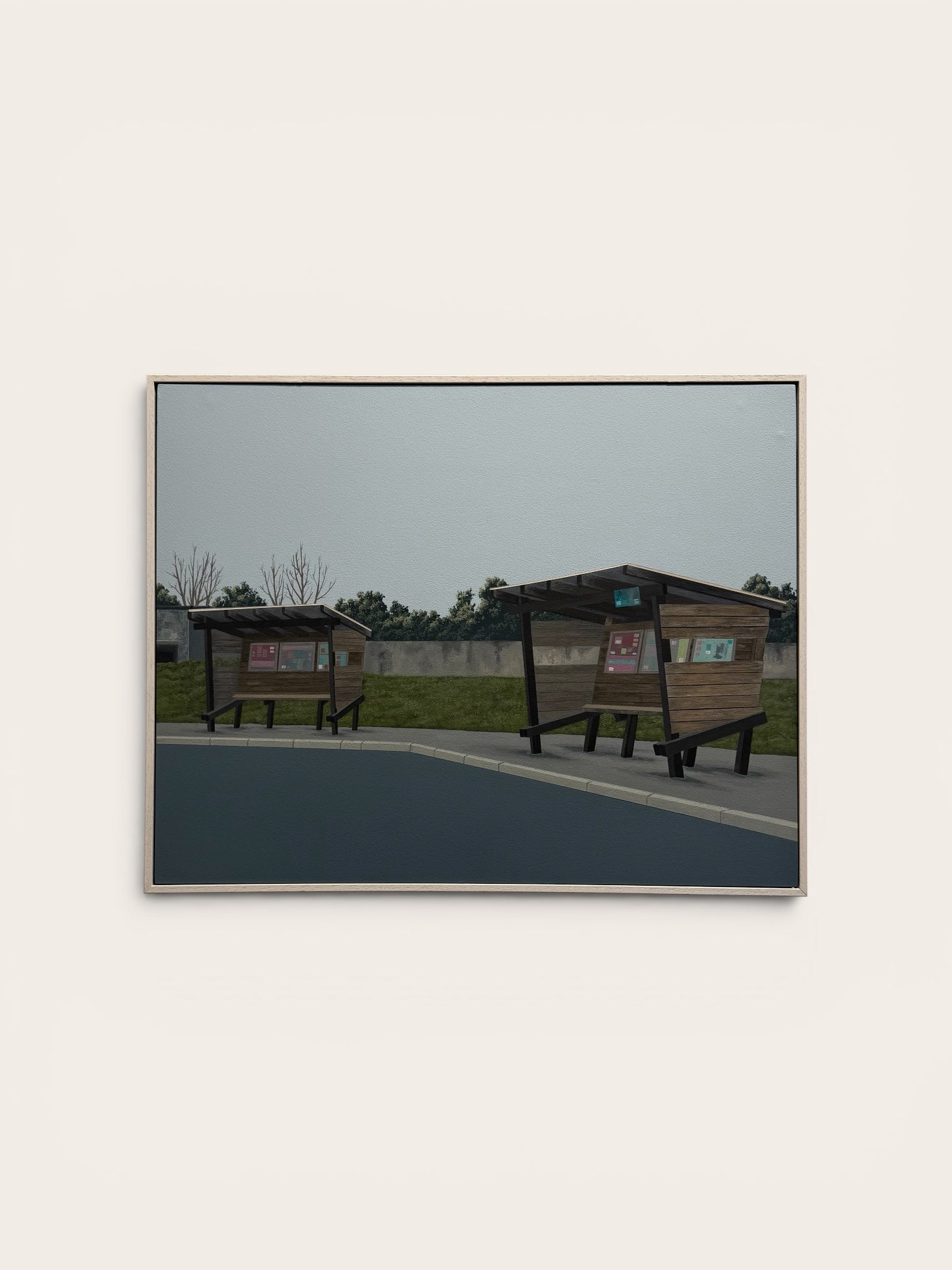 A framed photographic print depicting two wooden bus stop shelters on an overcast day, mounted on a light beige wall.