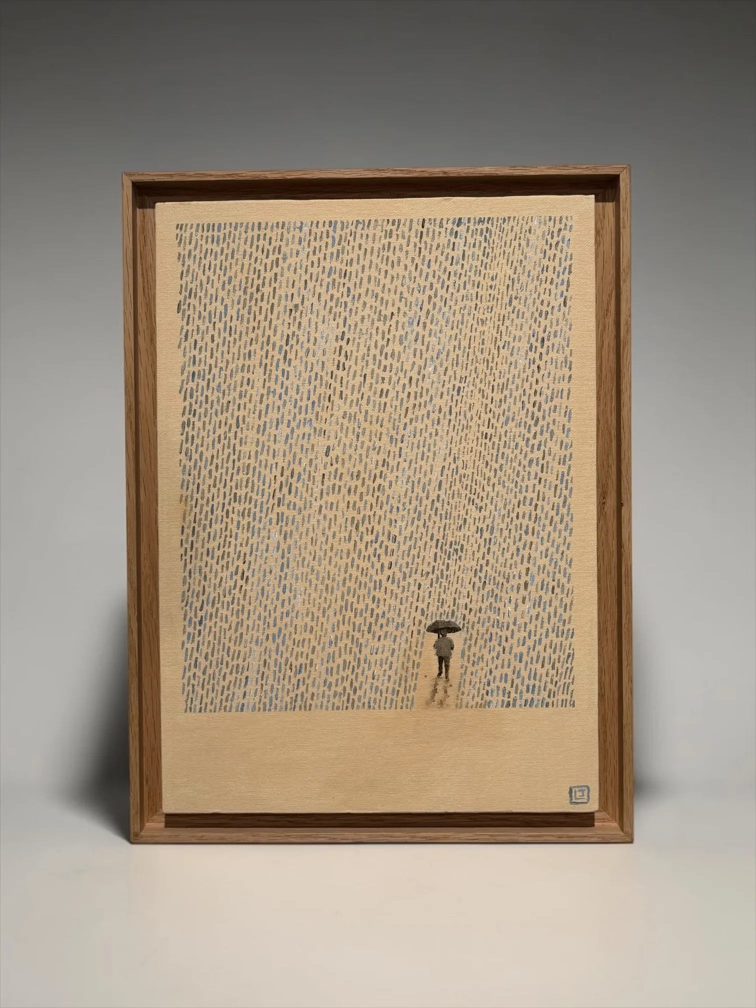 Framed artwork by Laine Jones 'The Storm" a small figure with an umbrella standing in a sea of text on a grey background
